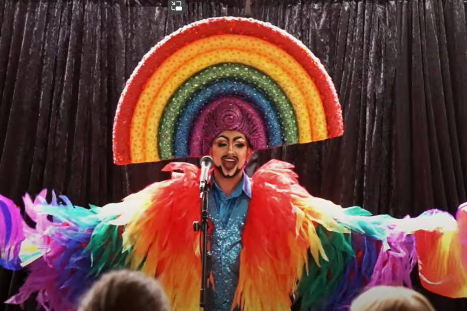 Drag KIng Hugo Grrrl in a rainbow feather outfit with rainbow headpiece